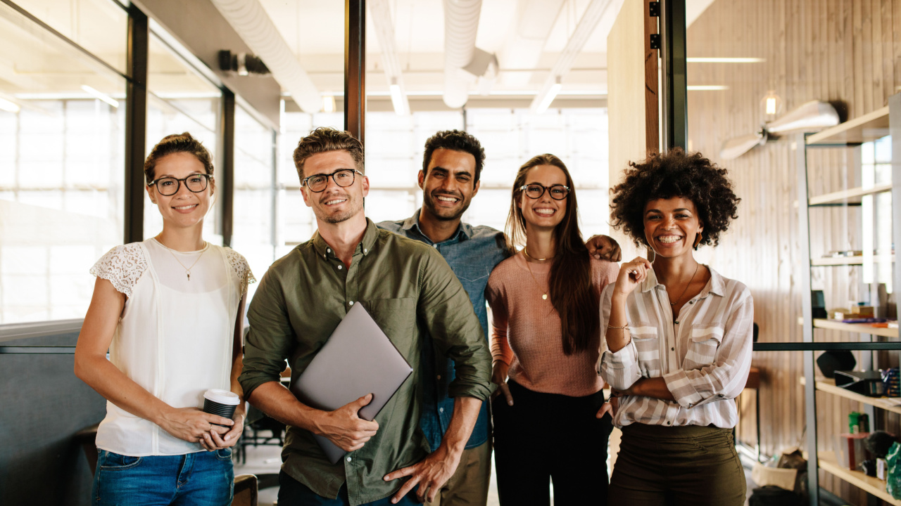 Happy diverse work team standing together in office setting