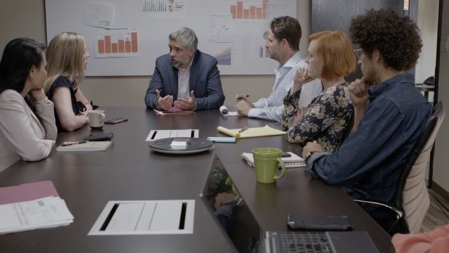 Male manager with diverse team sitting in conference room discussing respectful workplace standards