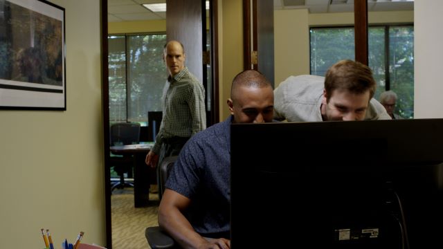 Two men close looking at computer screen