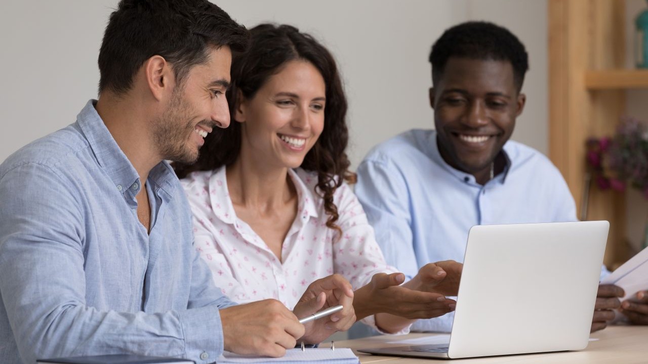 Three co-workers viewing a computer screen and sharing in a learning moment