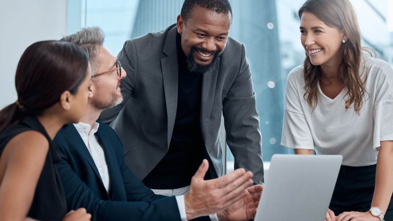 diverse work team reviewing results on a laptop, smiling