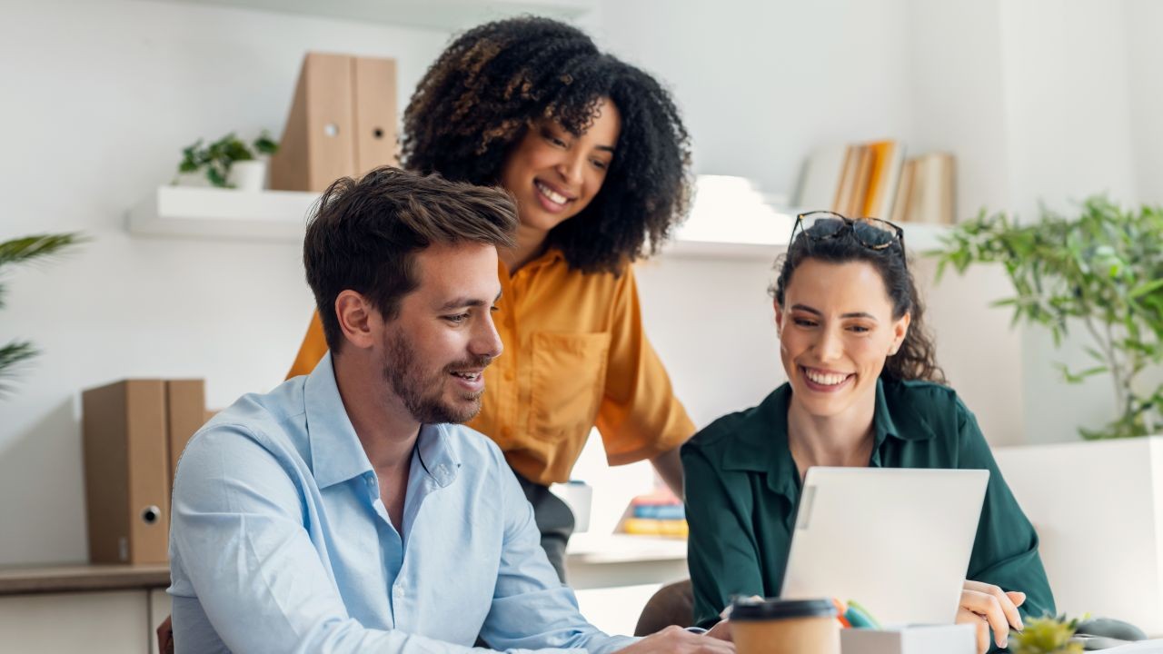 manager and two employees smiling, looking at computer